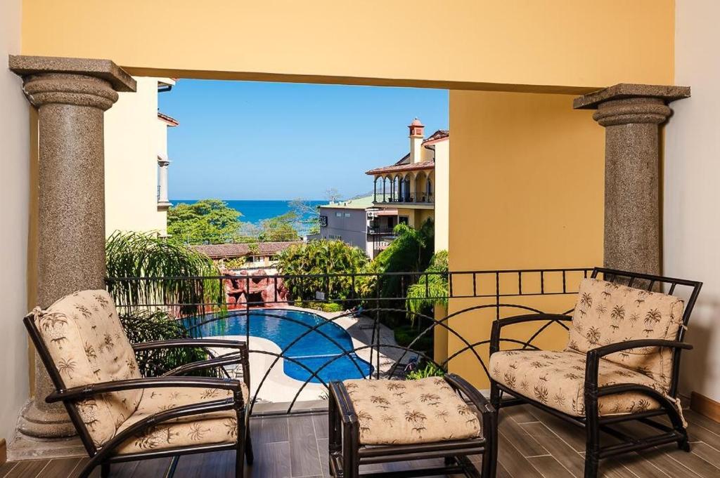 a balcony with two chairs and a swimming pool at Wake Up to Ocean Views, Pool, Walk to Sandy Beach in Tamarindo