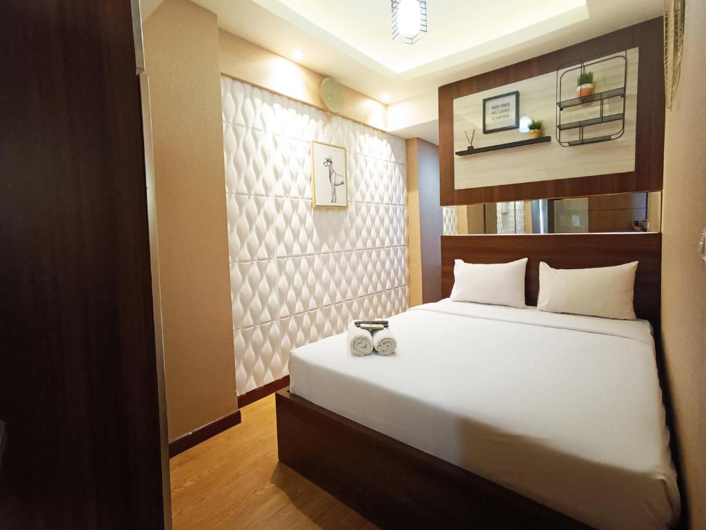 a bedroom with a white bed and a wall at Comfort and Strategic 2BR Apartment at Vida View Makassar By Travelio in Pampang