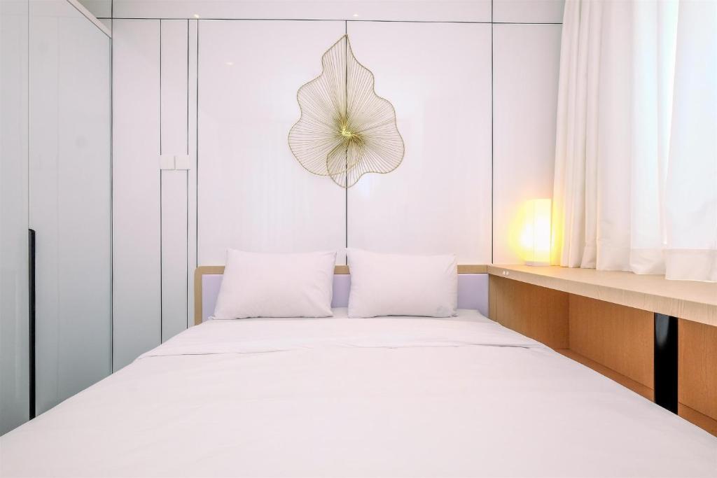 a bedroom with a bed with a flower on the wall at Good Deal 2BR at High Floor Transpark Cibubur Apartment By Travelio in Depok