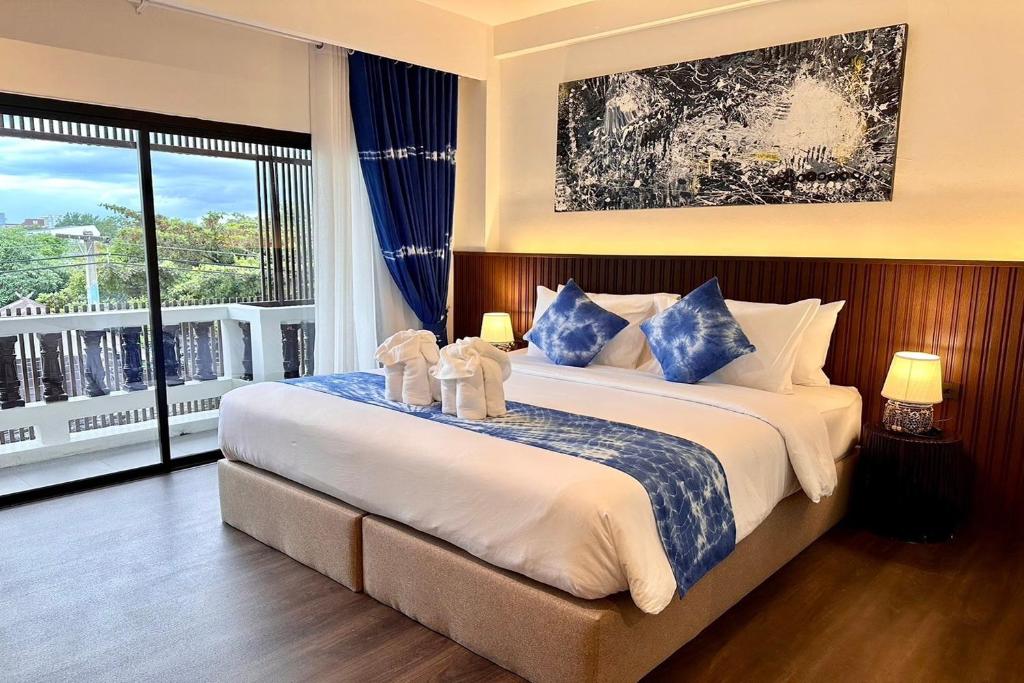 a bedroom with a large bed and a large window at Nuan Nil Secret Courtyard in Chiang Mai