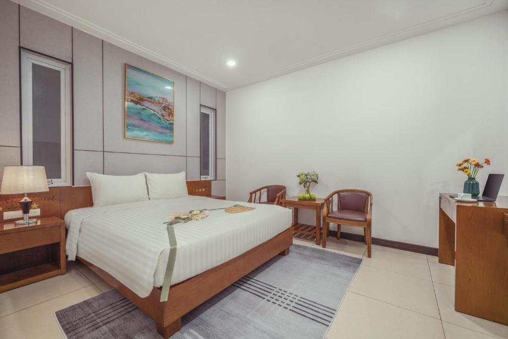 a bedroom with a bed and a desk and a chair at Star Hotel and Spa Danang in Danang