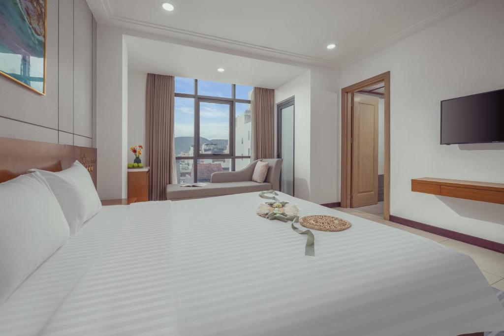 a bedroom with a large white bed with a flat screen tv at Star Hotel and Spa Danang in Danang