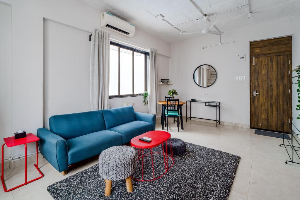 a living room with a blue couch and a table at Quirky 1BHK Bandra W by The Bombay Home Company in Mumbai