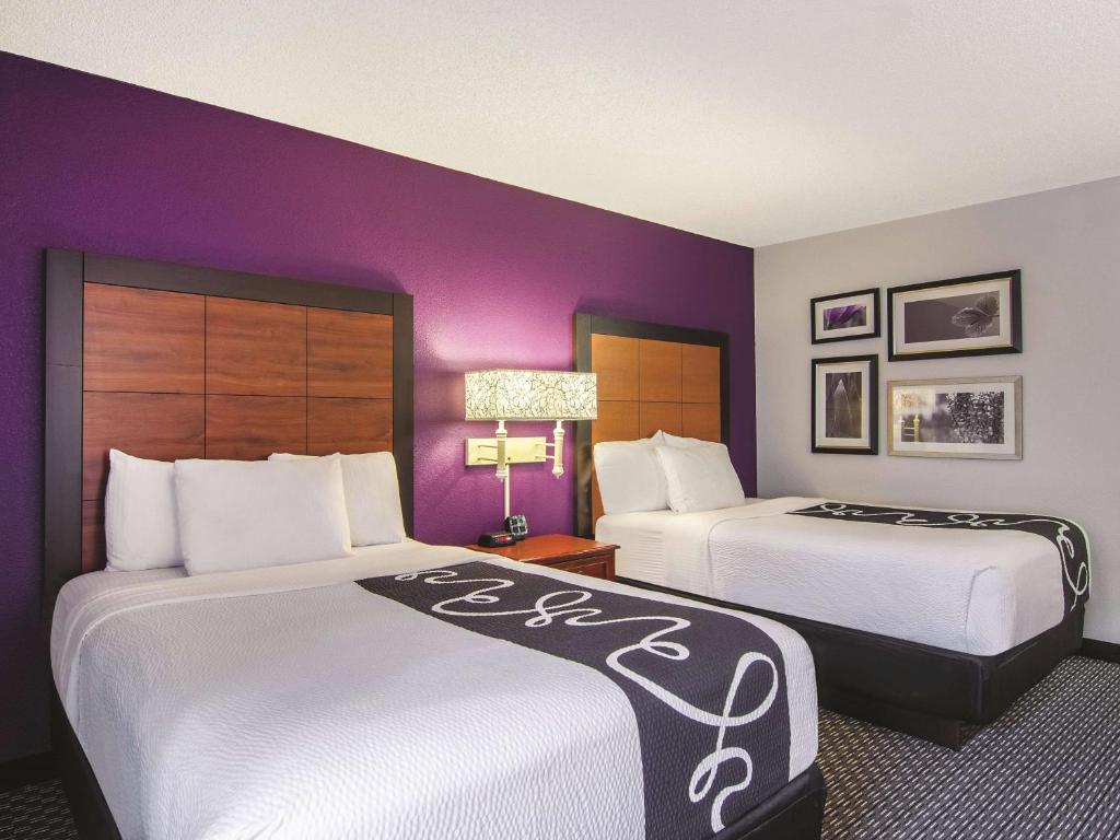 two beds in a hotel room with purple walls at Wingate by Wyndham Brunswick GA I-95 in Brunswick