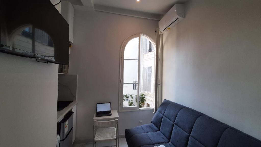 un salon avec un canapé bleu et une fenêtre dans l'établissement Winter Palace Beauséjour, à Cannes