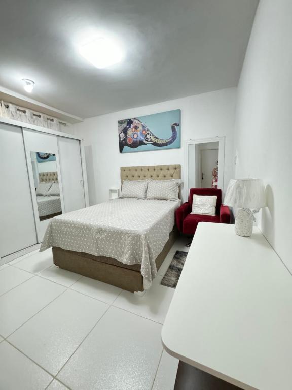 a white bedroom with a bed and a red chair at Residencial 95 del in Belém