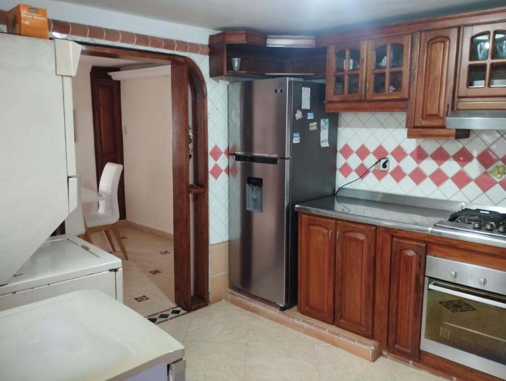 a kitchen with wooden cabinets and a stainless steel refrigerator at Casa Ciudad Jardin in Barranquilla