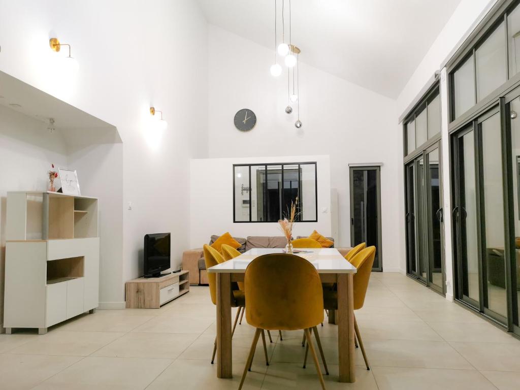 ein Esszimmer mit einem Tisch und gelben Stühlen in der Unterkunft Ker EL-RAPHA in Saint-Avé
