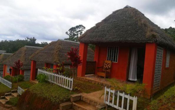 une petite maison rouge avec un toit de chaume dans l'établissement GO Andasibe Hotel, à Andasibe