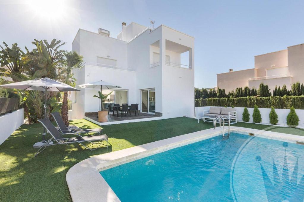 a villa with a swimming pool in front of a house at La Manga Club Las Mimosas Villa 608 in Atamaría
