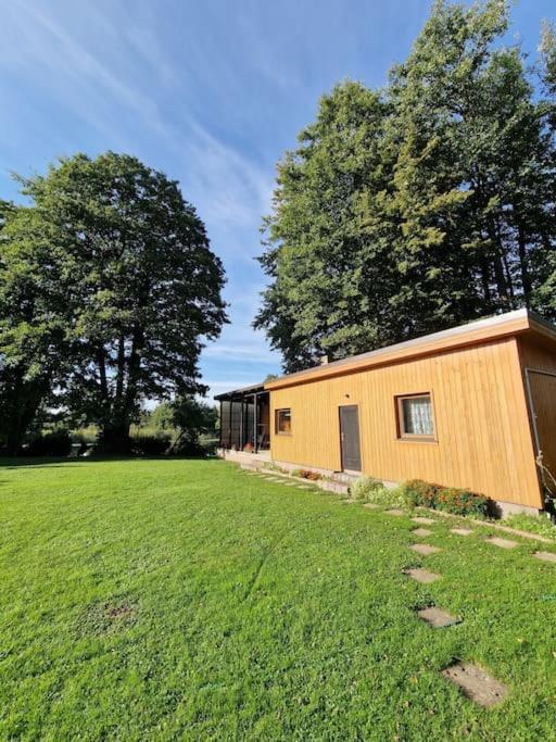 a small building in a field next to trees at Ezermalas in Carnikava