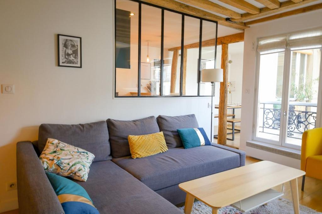 un salon avec un canapé bleu et une table dans l'établissement Appartement Chic & Spacieux | Paris 2ème, à Paris