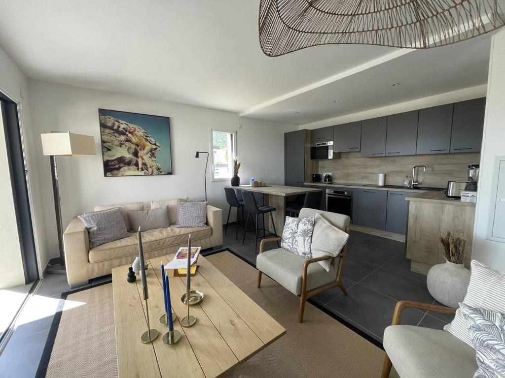 un salon avec un canapé et une cuisine dans l'établissement Charmant T3 dans une résidence neuve avec piscine, à Calvi