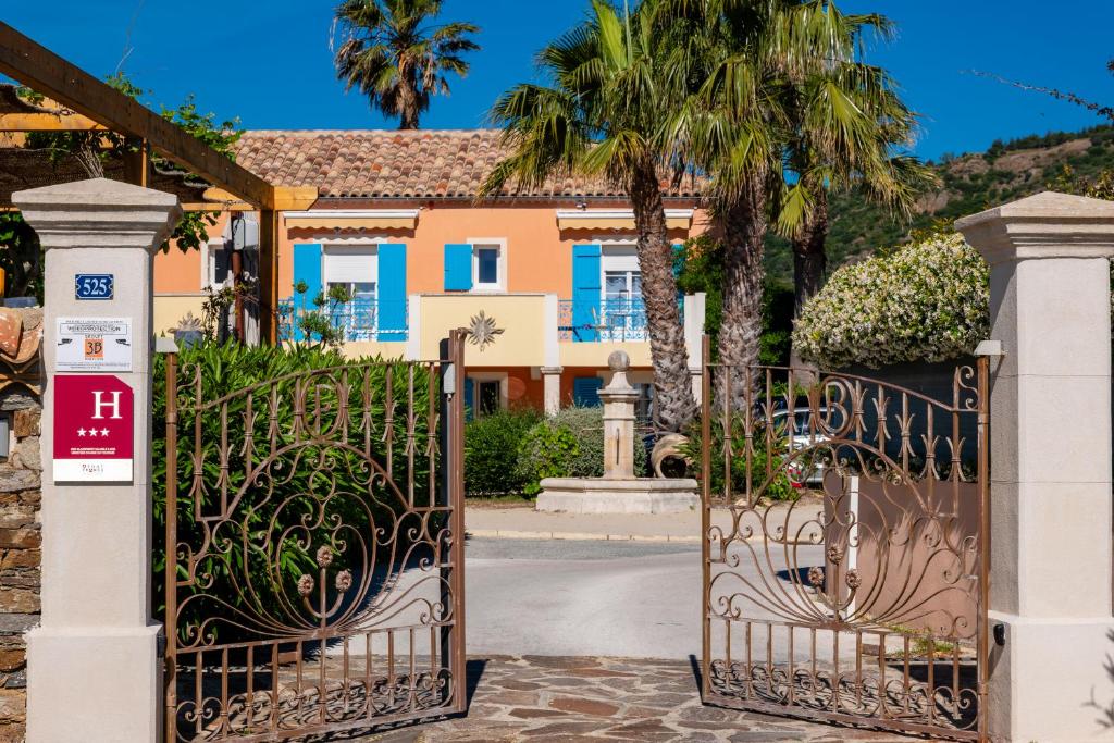 a gate to a house with a palm tree at Hotel Les Flots Bleus in Le Lavandou