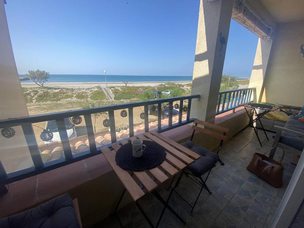 - un balcon avec une table et des chaises et la plage dans l'établissement Appartement sur la plage - parking - terrasse vue mer - 1er étage, à Saintes-Maries-de-la-Mer