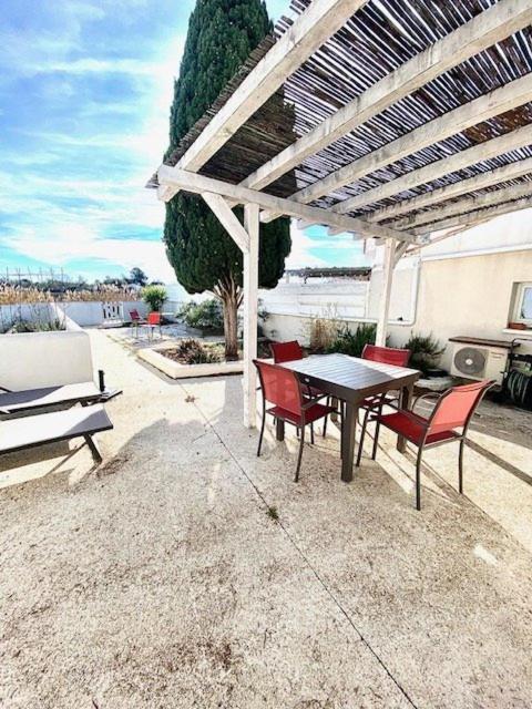 un patio avec une table et des chaises sous une pergola dans l'établissement Maison, jardinet, terrasse, parking privée, climatisation, à Saintes-Maries-de-la-Mer