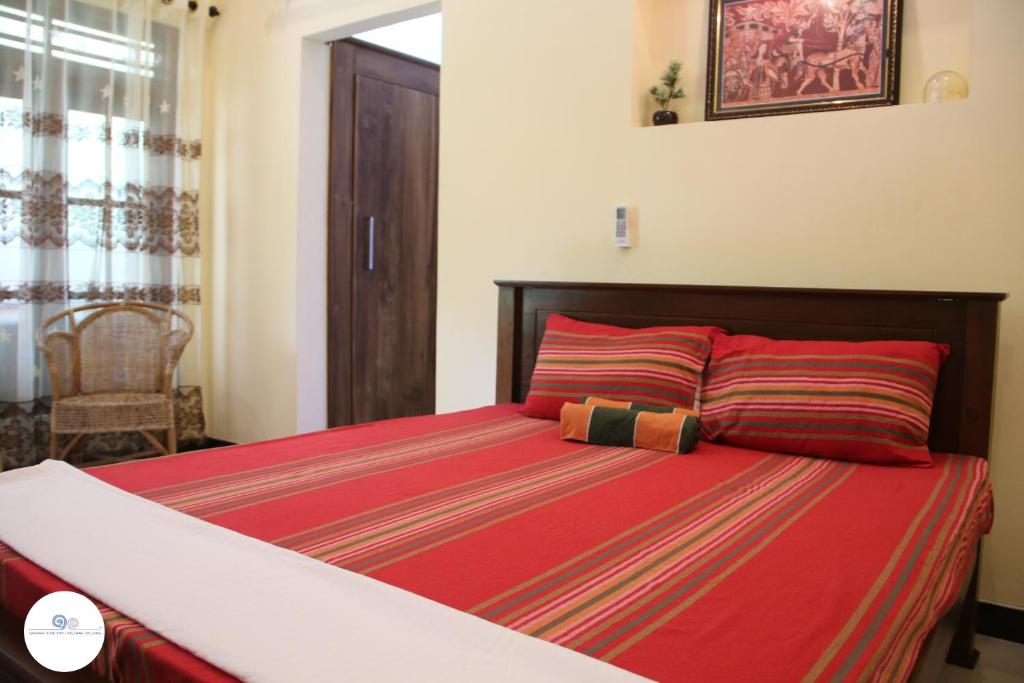 a bedroom with a large bed with red sheets at Sawanga Home Stay in Weligama