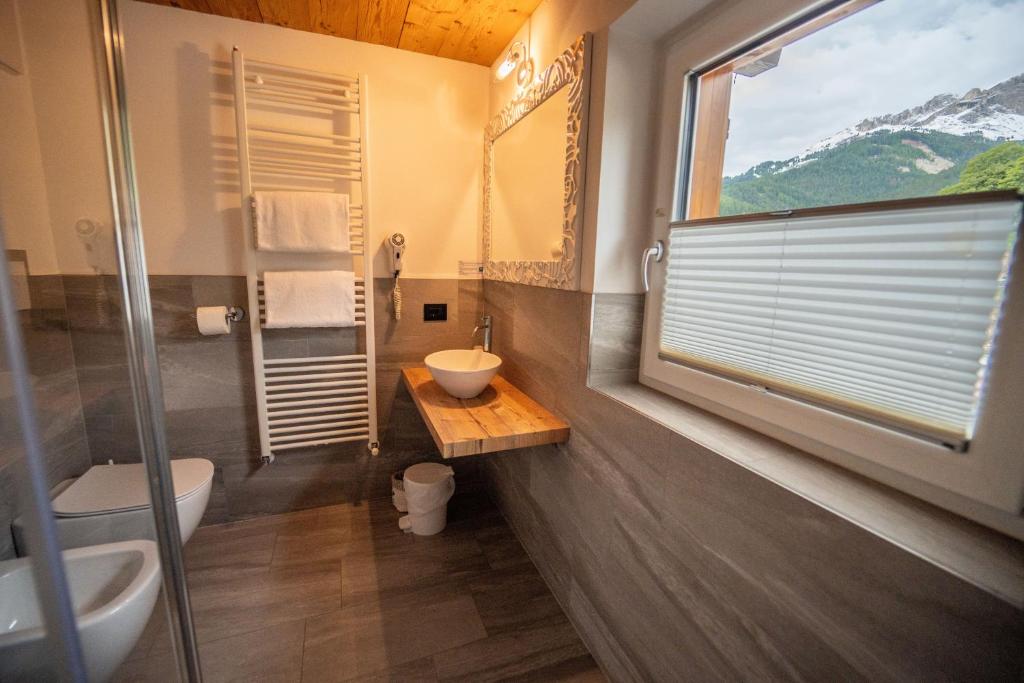 łazienka z toaletą, umywalką i oknem w obiekcie B&B Bucaneve w mieście Vigo di Fassa