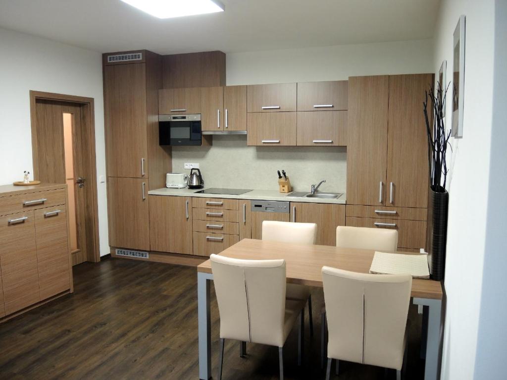 a kitchen with a wooden table and white chairs at Apartmány na Dolní Moravě in Dolní Morava