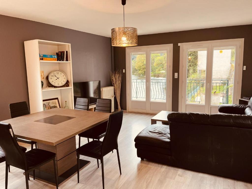 un salon avec une table et un canapé dans l'établissement Maison sur les bords de Cere, Laroquebrou, balcon terrasse 3 chambres, à Laroquebrou
