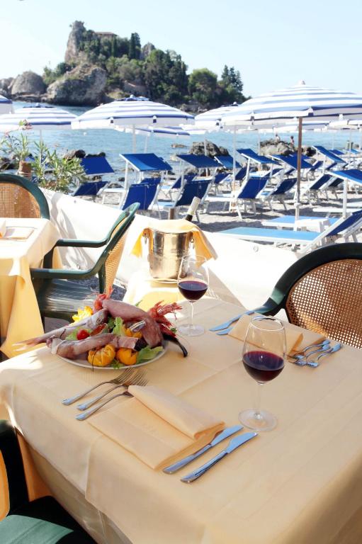 a table with a plate of food and glasses of wine at Mendolia Beach Hotel in Taormina