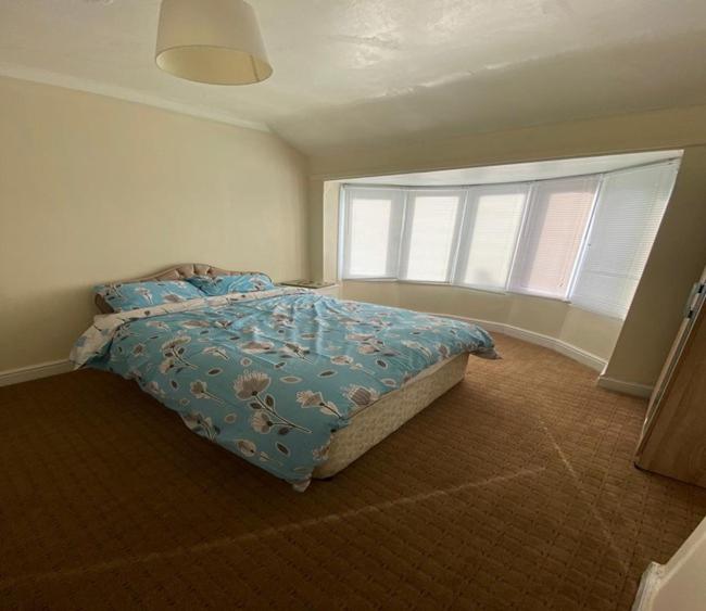a bedroom with a bed with a blue comforter and a window at Birchfield Place in Birmingham