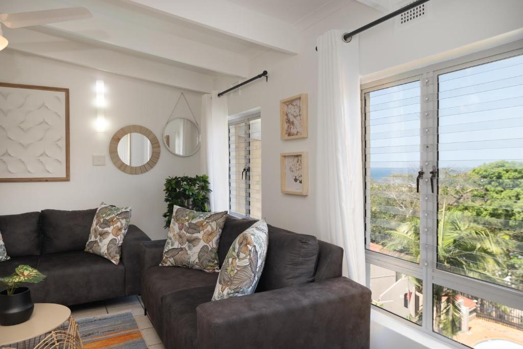 un soggiorno con un divano e una grande finestra di Chakas Rock Chalets 49 a Ballito