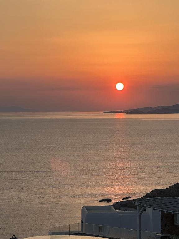 a sunset over a body of water with the sun setting at Myconian Sunset Apartments in Tagou