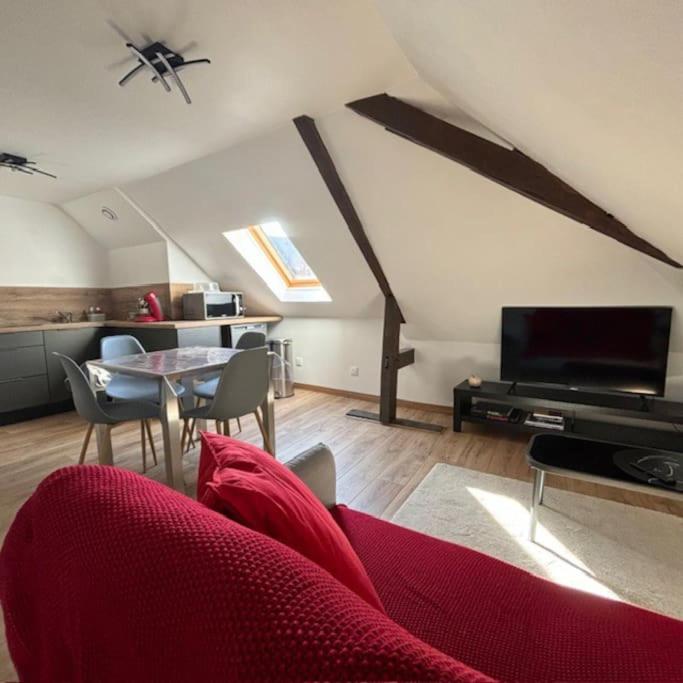 un salon avec un canapé rouge et une table dans l'établissement Appartement 2 personnes, à Lestrem