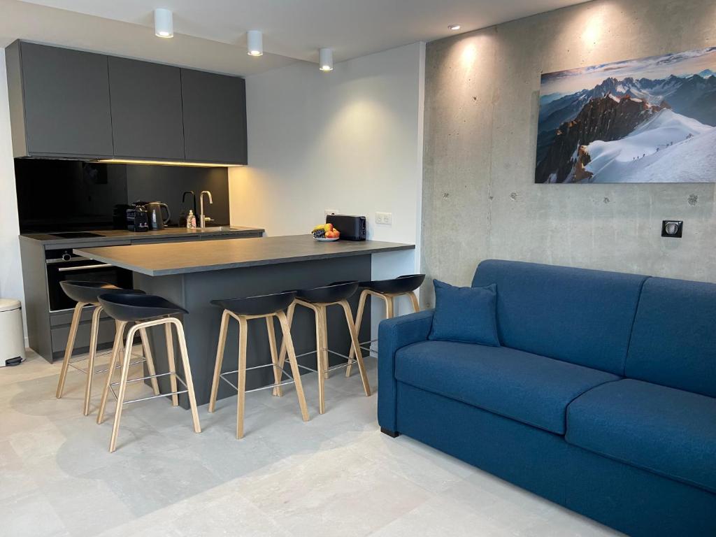 a living room with a blue couch and a kitchen at AltiPAM Lodge Val Thorens in Val Thorens