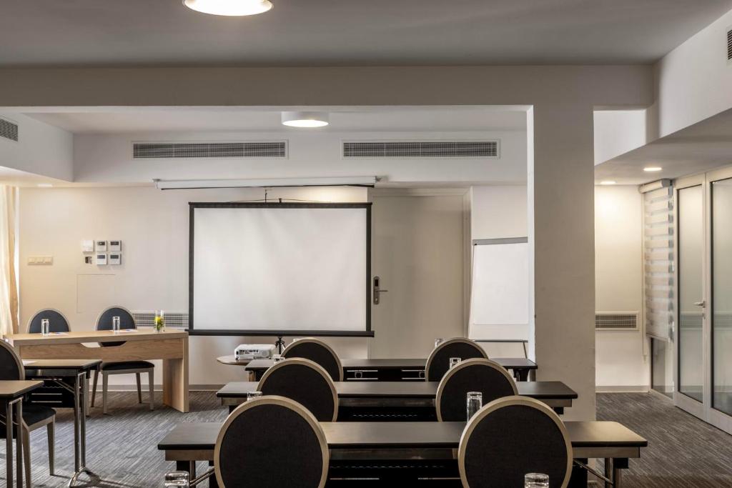 a classroom with tables and chairs and a projection screen at Park Beach Hotel in Limassol
