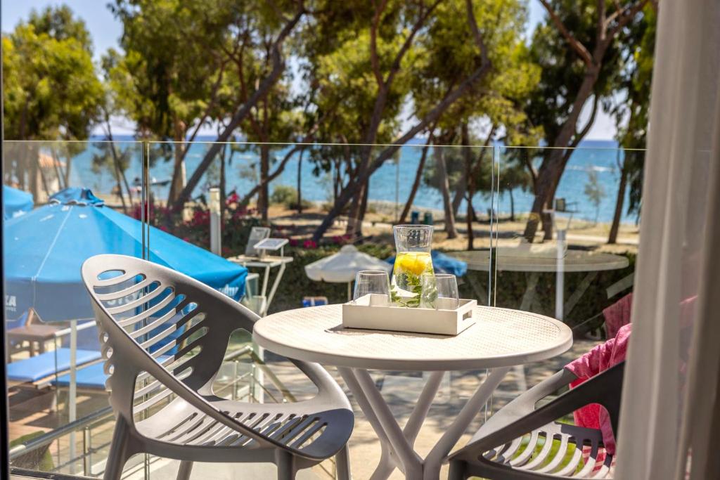 a table and chairs with a drink on a balcony at Park Beach Hotel in Limassol