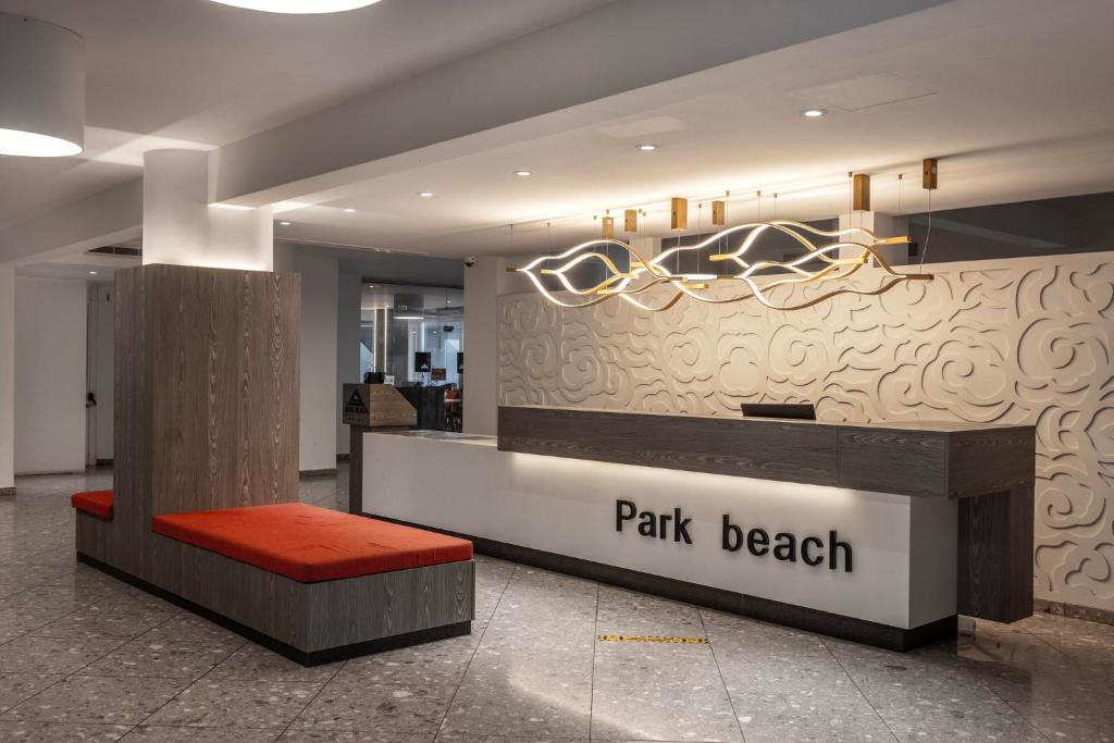 a lobby with a park beak counter with a red bench at Park Beach Hotel in Limassol