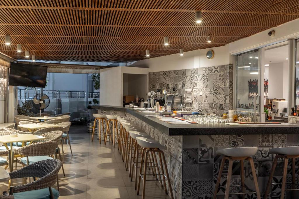a restaurant with a bar with chairs and tables at Park Beach Hotel in Limassol
