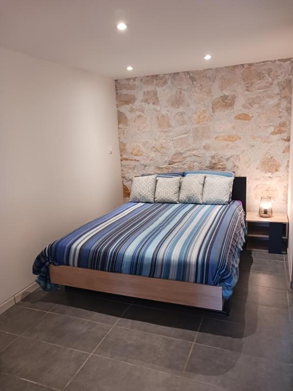 une chambre avec un lit et un mur en pierre dans l'établissement Joli studio au calme, à Crégandie