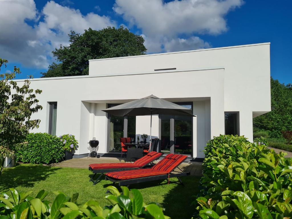 une maison blanche avec des chaises rouges et un parasol dans l'établissement Eilers, Katja Lilly, Ferienwohnung Lilly, à Varel