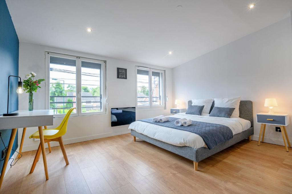a bedroom with a bed and a desk and windows at Le Louvre Lens - Premium - Wifi - Balcon & Parking in Lens
