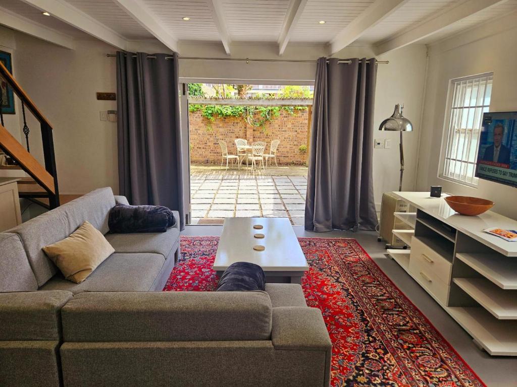 ein Wohnzimmer mit Sofa und Tisch in der Unterkunft PinotageLuxuryCollection 9A Herte Suite in Stellenbosch