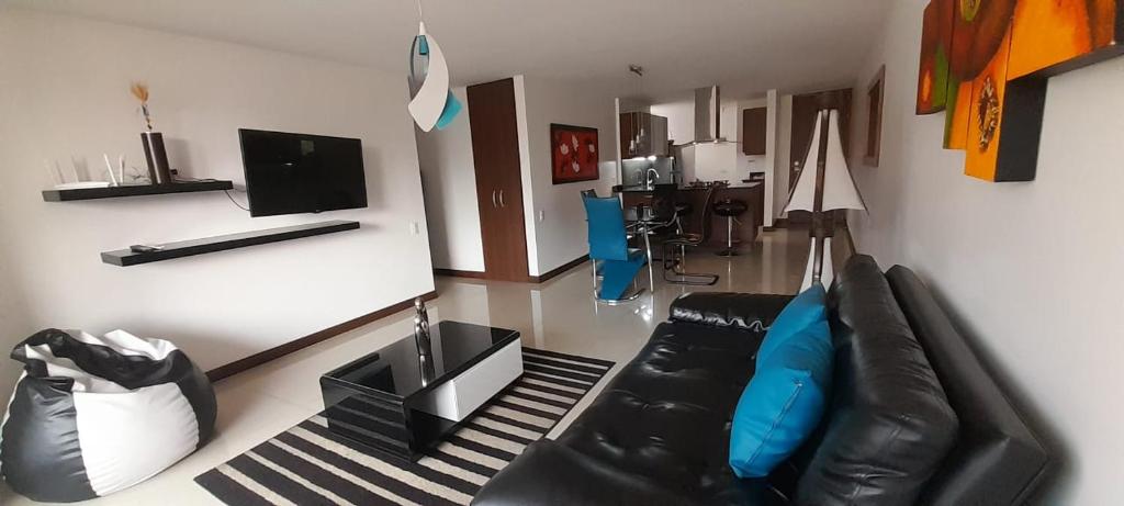 a living room with a black leather couch and a television at Lujoso y Economico Apartamento in Envigado