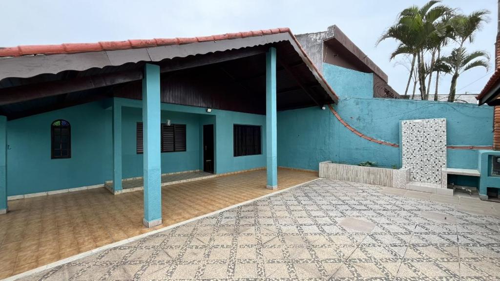 a blue building with blue columns and a courtyard at Doce Lar in Itanhaém