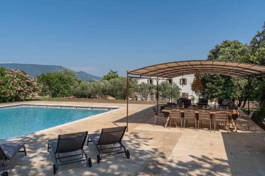 un patio avec une table et des chaises à côté d'une piscine dans l'établissement Domaine des 3 Fontaines, à Saint-Saturnin-lès-Apt