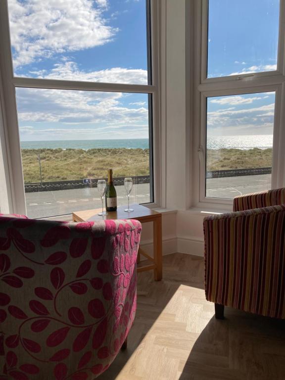 Habitación con mesa, 2 sillas y ventana en Barmouth Beach Front Apartments, en Barmouth