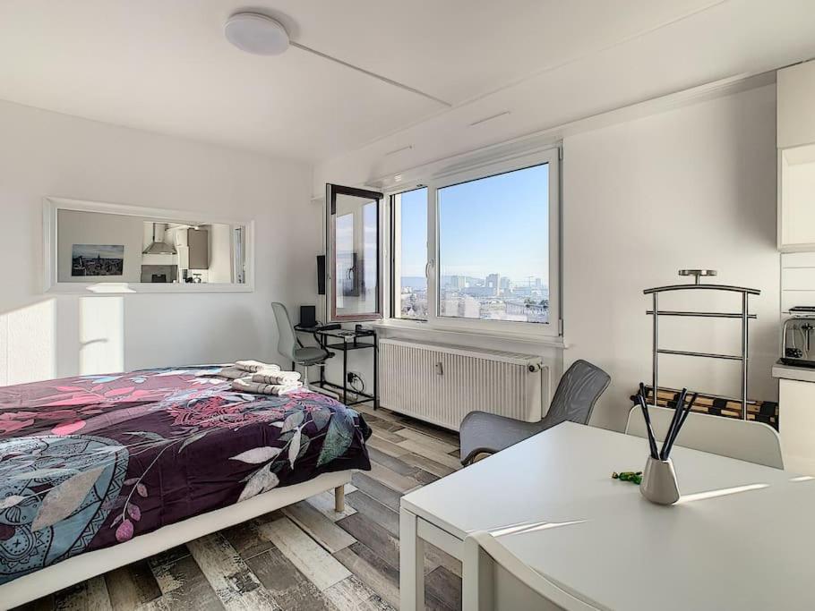 a bedroom with a bed and a table and a window at Studio 8 - proche tram, Bâle, autoroute in Bourgfelden
