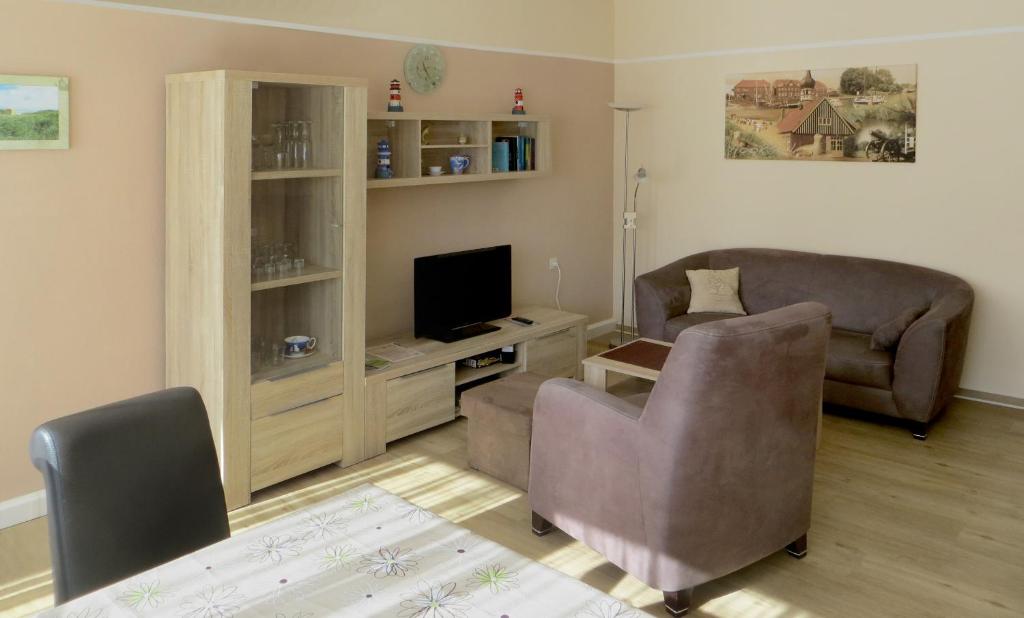 Una sala de estar con un sofá y un televisor. en Ferienwohnung Klabautermann, en Hooksiel
