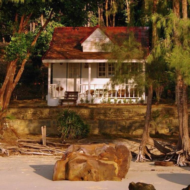 a white house with a rock in front of it at Pansand Resort in Ko Bulon Le