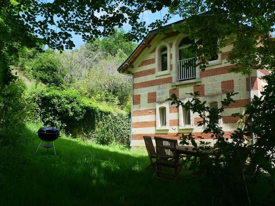 a house with a grill and two chairs in the yard at Magnifiques Ecuries juste rénovées - Domaine de la Mulotière in Langeais