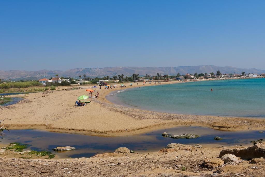 a group of people on a beach with the water at Astro apartments with direct access on the sea of Noto heritage of Unesco in Noto
