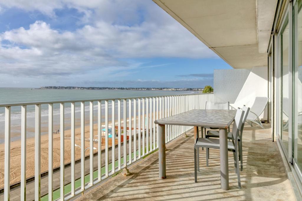 a table and chairs on a balcony overlooking the beach at Pieds dans l'eau - Balcon vue mer in La Baule