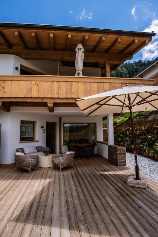a wooden deck with an umbrella and a table at K-Style Chalet Premium-Twin-Lofts with private Sauna in Mieders