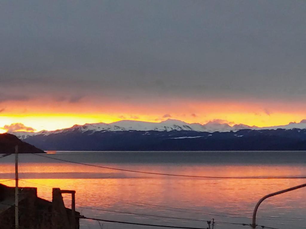 ein Sonnenuntergang über einem Gewässer mit Bergen in der Unterkunft Balcones del Beagle Apart in Ushuaia